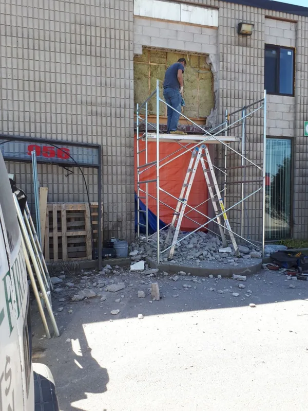 New opening cut into the block wall of a commercial building, with scaffolding set up outside