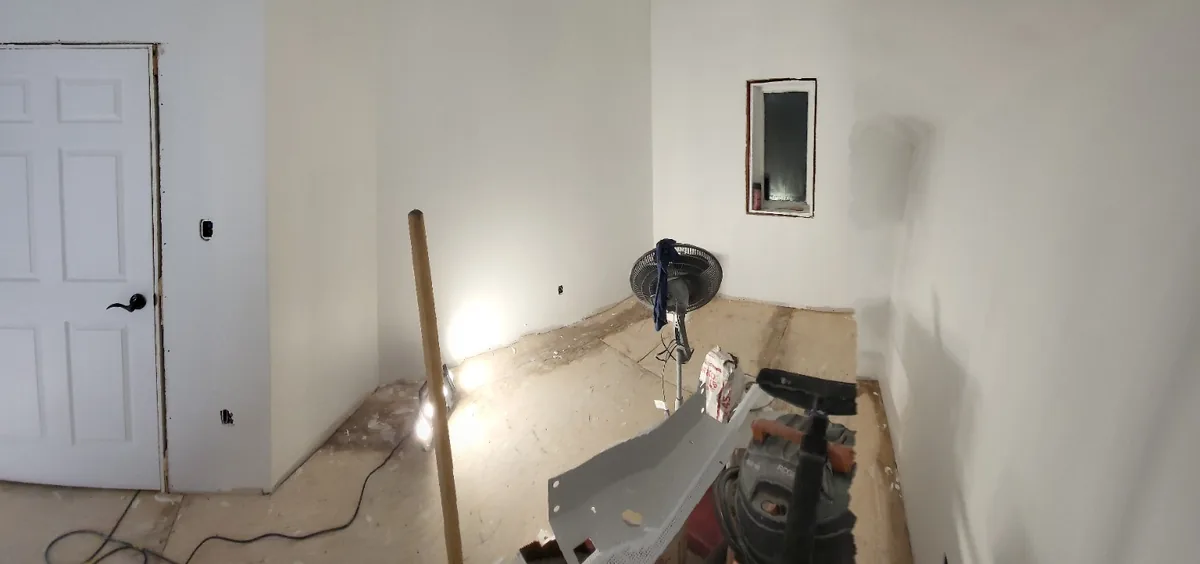 Interior room with a section of floor opened up for services, walls boarded around it