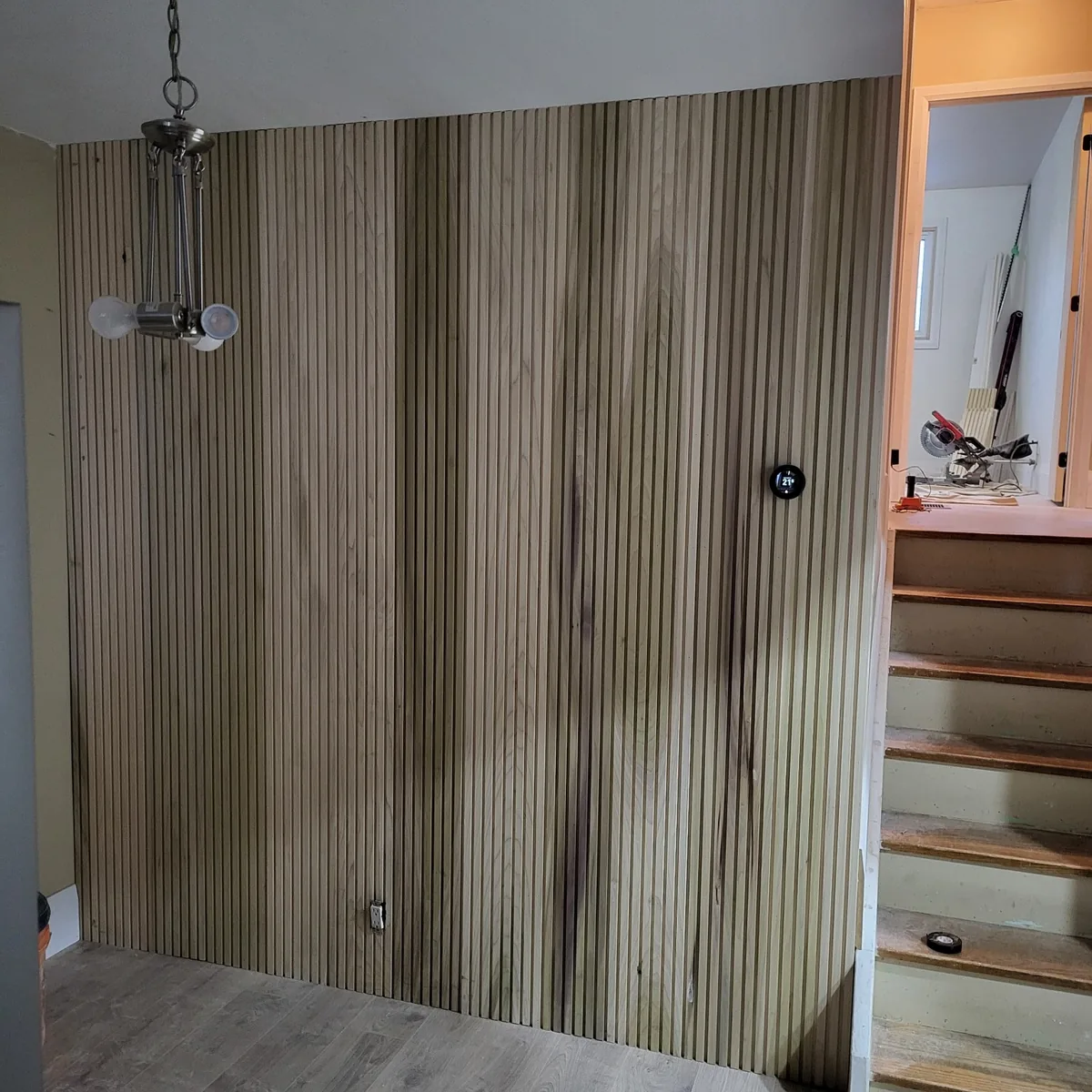Vertical wood slat feature wall beside a staircase, with the trim and flooring complete